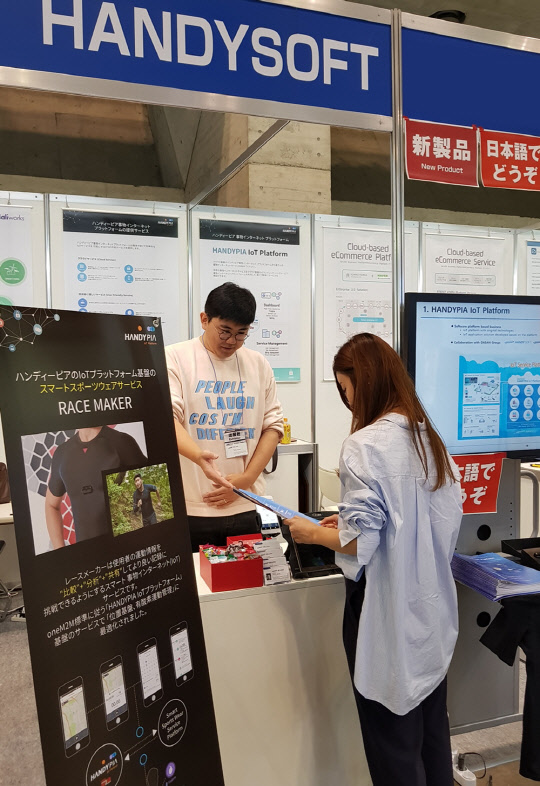 핸디소프트는 일본 IT 최대 전시회인 재팬 IT 주간에 IoT 플랫폼 '핸디피아'와 스마트 스포츠웨어 서비스 '레이스메이커'를 소개하는 전시부스를 열었다. 관람객이 핸디피아 부스를 방문해 설명을 듣고 있다.  핸디소프트 제공